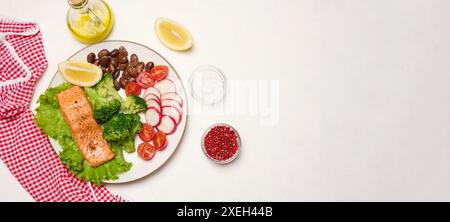 Gesundes Mittagessen mit gegrilltem Lachs auf grünem Salat, neben Gemüse, Tomaten, Radieschen, Brokkoli und einer Portion Bohnen. Stockfoto