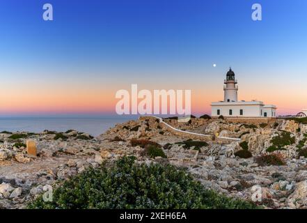 Blick auf den Leuchtturm Cap de Cavalleria auf Menorca bei Sonnenuntergang bei Vollmond Stockfoto