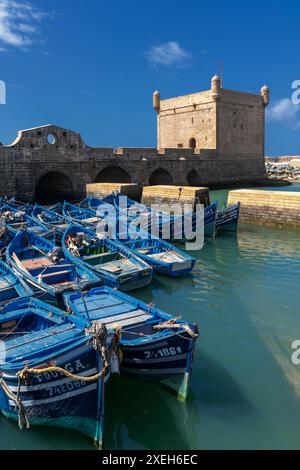 Der Wachturm Borj el Barmil und die farbenfrohen blauen Fischerboote im alten Hafen von Essaouira Stockfoto