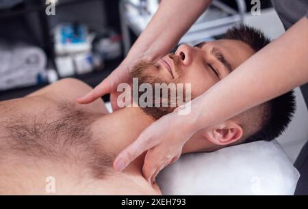 Nahporträt eines jungen attraktiven Mannes, der eine Gesichtsmassage bekommt Stockfoto