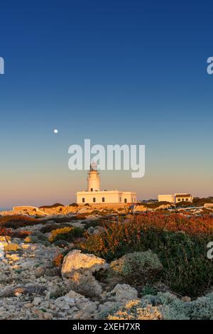 Senkrechte Ansicht des Leuchtturms Cap de Cavalleria auf Menorca bei Sonnenuntergang mit Vollmondaufgang Stockfoto