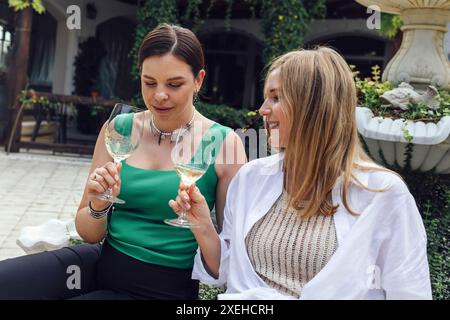 Zwei attraktive Freundinnen in lässiger Kleidung sitzen im Open-Air-Café. Stockfoto