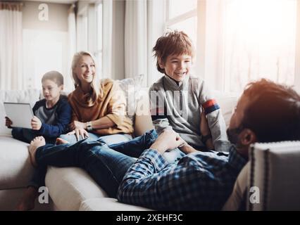 Eltern, Kinder und Familie mit dem Spielen auf Sofa, Tablet und mit Liebe, Witz oder lustigen Erinnerungen im Wohnzimmer. Mutter, Vater und Kinder mit Stockfoto