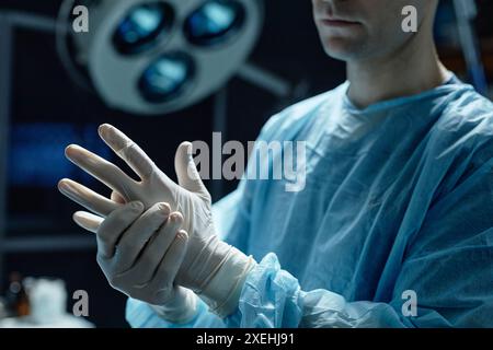 Abgeschnittene Aufnahme eines Chirurgen mit Schutzhandschuhen zur Vorbereitung der Operation im Kopierraum im Operationssaal Stockfoto