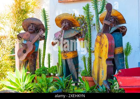 San Diego, Kalifornien - 16. April 2024: Rustikale Metallskulpturen von drei Mariachi-Band-Musikern, die Instrumente in einem Garten spielen. Stockfoto