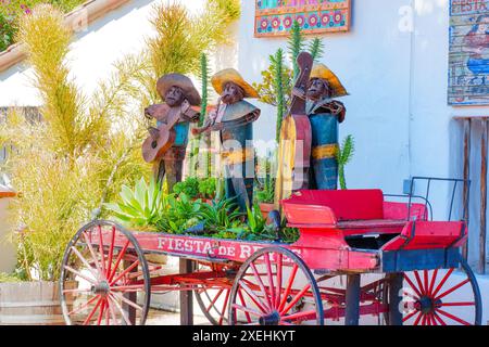 San Diego, Kalifornien - 16. April 2024: Rustikale Metall-Mariachi-Band-Skulpturen auf einem alten dekorierten Wagen, umgeben von Grün vor dem Stockfoto