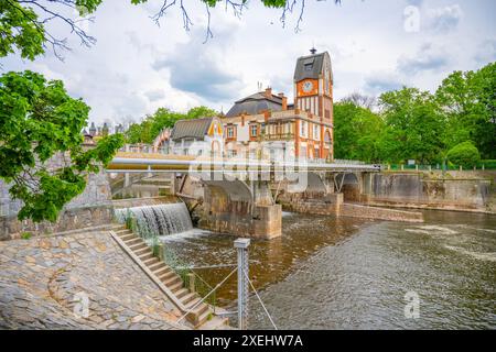 Das Jugendstilgebäude des Wasserkraftwerks Hucak in Hradec Kralove, Tschechien, ist mit einer Brücke über einen fließenden Fluss abgebildet. Stockfoto