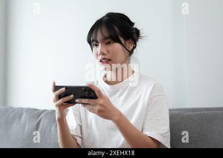 Asiatische Frau, die auf dem Handy spielt. Gamer Mädchen, das Videospiele spielt und SmartphoneÂ funktionierende mobile Geräte hält. Handy-Teleph Stockfoto