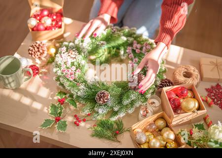 Frau, die Mistelkranz macht Weihnachtskranz Dekoration mit handgemachten DIY Winter Grün Blumenhändler Hände machen Weihnachtswrea Stockfoto