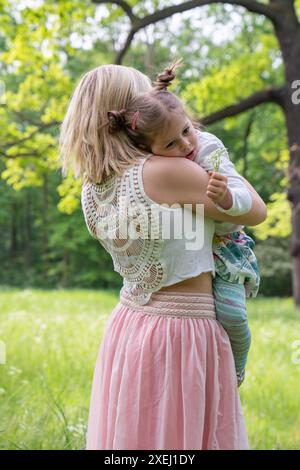 Mom hält sanft ein kleines Mädchen in den Armen. Trost, Mutter Liebe, Fürsorge. Spazieren Sie im Park. Familienkonzept Stockfoto