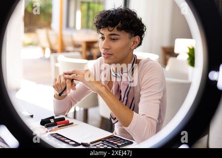 Make-up zu Hause auftragen, Transgender-Frau mit Kosmetik und Schönheitswerkzeugen Stockfoto