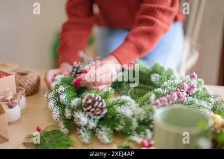 Frau, die Mistelkranz macht Weihnachtskranz Dekoration mit handgemachten DIY Winter Grün Blumenhändler Hände machen Weihnachtswrea Stockfoto