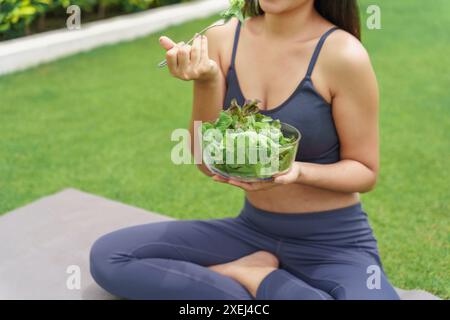 BeautifulÂ Zuversicht Fitness asiatische Frau essen gesunden Salat nach dem Training. Yoga-Training im grünen Park Stockfoto