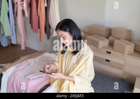 Beschäftigte asiatische Frau, die Paketzustellbox vorbereitet Versand für Einkäufe online Smartphone Mädchen Start up Kleinunternehmer Inhaber onli Stockfoto