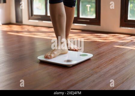 Fettdiät und Schuppenfüße stehen auf elektronischen Waagen zur Gewichtskontrolle. Messgerät in Kilogramm für eine Diätkontrolle Stockfoto