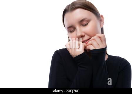 Porträt eines träumenden kaukasischen Mädchens, gekleidet in einem schwarzen Rollkragenkragen auf weißem Hintergrund Stockfoto