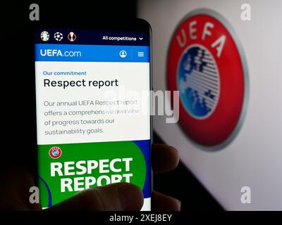 Person mit Smartphone und Website der Union Europäischer Fußballverbände (UEFA) vor dem Logo. Konzentrieren Sie sich auf die Mitte des Telefondisplays. Stockfoto