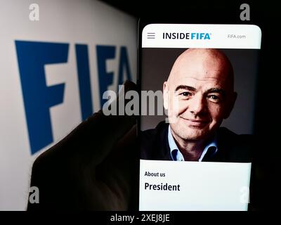 Person, die ein Mobiltelefon mit der Website der Federation Internationale de Football Association (FIFA) mit Logo hält. Konzentrieren Sie sich auf die Mitte des Telefondisplays. Stockfoto