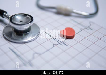 Nahaufnahme eines Stethoskops und eines roten Herzens auf einem Elektrokardiogramm (EKG)-Ausdruck. Das EKG-Diagramm zeigt einen normalen Sinusrhythmus. Stockfoto