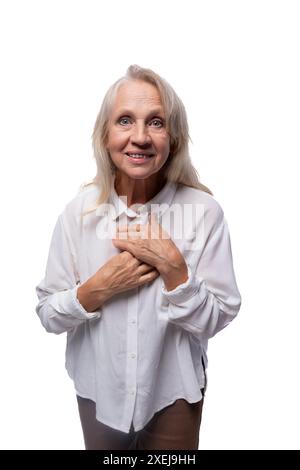 65 Jahre alte glückliche europäische reife Frau, die Hemd auf weißem Hintergrund trägt Stockfoto