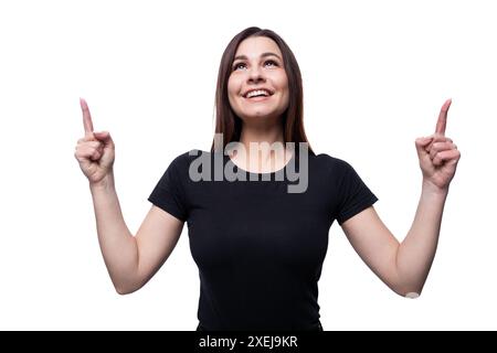 Eine junge selbstbewusste Frau mit schwarzen Haaren in einem schwarzen T-Shirt zeigt ihre Hände hoch Stockfoto
