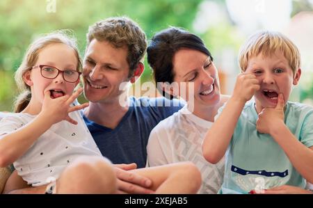Outdoor, Vater und Mutter mit Kindern im Porträt, lustige Gesichter, verspielt und als Familie verbunden. Hinterhof, Dad und Mom mit Kindern als Eltern Stockfoto
