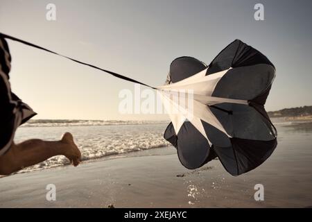 Männlicher Athlet trainiert mit einem Fallschirm an einem Strand in La Jolla, CA. Stockfoto