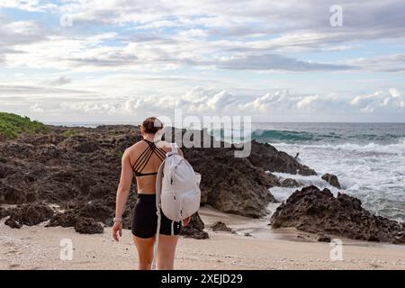 Frau wandert an einem felsigen Strand in Hawaii entlang. Stockfoto