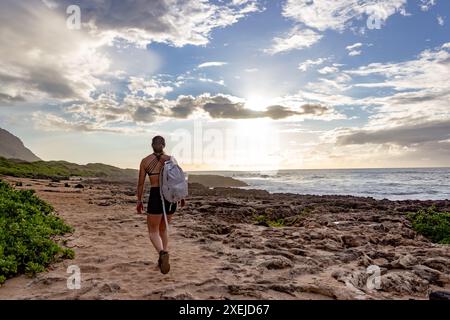 Frau wandert am Strand bei Sonnenuntergang auf Hawaii entlang. Stockfoto