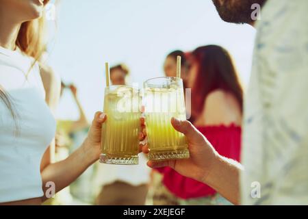 Cooler Sommer-Vibe. Nahaufnahme von zwei Freunden, die mit verschiedenen Getränken anstoßen und die Freude und Kameradschaft des Moments festhalten. Stockfoto