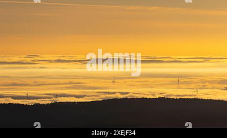 Morgenlicht über nebeliger Landschaft mit Windmühlen und dramatischem Himmel Stockfoto