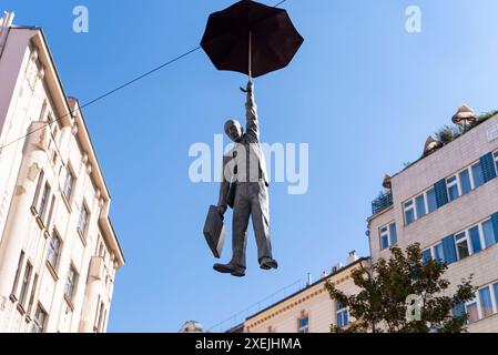 Statue einer Frau, die mit einem orangefarbenen Regenschirm hängt. Kunstaufführung in Prag, Tschechische Republik Stockfoto