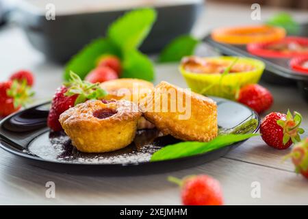 Süße Quark-Muffins mit Erdbeerfüllung, auf einem Teller auf einem Holztisch. Stockfoto