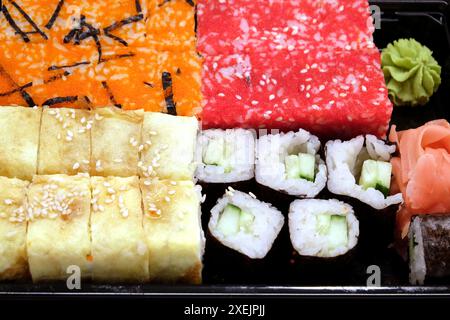 Appetitliche frische Sushi-Stücke auf schwarzem Küchentablett, Vorderansicht aus nächster Nähe Stockfoto