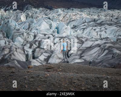 Mann mit Blick auf den riesigen Gletscher mit Gletscherspalten und Eisformationen in Island Stockfoto