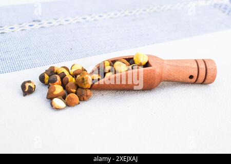 Makroaufnahme von schwarzen Kichererbsen (Cicer arietinum) oder Kala Chana auf einem weißen KeramikSuppenlöffel. Draufsicht, über einem verlaufenen Hintergrund des Isels Stockfoto