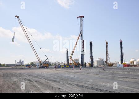 Stade, Deutschland. Juni 2024. Ein Kran und andere Baumaschinen stehen auf einer Baustelle während des offiziellen Spatenstichs für das erste landgestützte Terminal für Flüssiggase in Deutschland. Das LNG-Terminal in Stade bei Hamburg soll 2027 in Betrieb gehen. Quelle: Georg Wendt/dpa/Alamy Live News Stockfoto