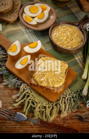 Eiersalat in einer rustikalen Schüssel, serviert mit in Scheiben geschnittenen hart gekochten Eiern und grünen Zwiebeln auf einem Tisch Stockfoto