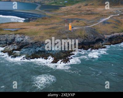 Blick aus der Vogelperspektive auf die zerklüftete isländische Küste mit Orange Building auf Cliff Stockfoto