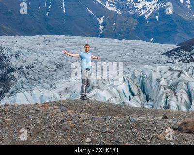 Mann mit ausgestreckten Armen, der den riesigen Gletscher in Island überblickt Stockfoto