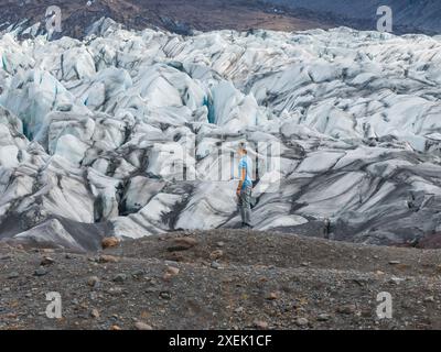 Der Mann steht auf einem Felsvorsprung mit Blick auf den riesigen isländischen Gletscher Stockfoto