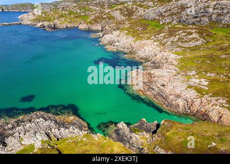 Achmelvich Sutherland Schottland mit Sommersonne über einer abgelegenen Bucht und klarem blauem, grünem Meer Stockfoto