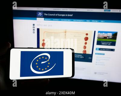 Person mit Smartphone und Logo der Menschenrechtsorganisation Europarat vor der Website. Schwerpunkt auf dem Display des Telefons. Stockfoto