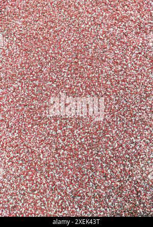 Nahaufnahme strukturierter roter Hintergrund aus Gummi-Laufbahnen im Leichtathletikstadion. Draufsicht. Sandkörner Stockfoto