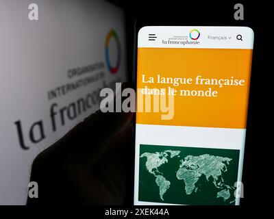 Person, die ein Mobiltelefon hält, mit der Webseite der Organisation Internationale de la Francophonie vor dem Logo. Konzentrieren Sie sich auf die Mitte des Telefondisplays. Stockfoto