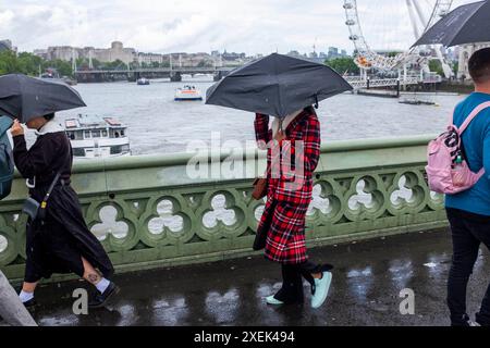 Frau in Schottenkaro mit einem Schirm über die Westminster Bridge im Sommerregen London, England, Großbritannien Stockfoto