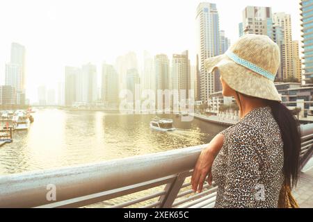 Dubai, VAE - 12.. oktober 2022: Wunderschöne kaukasische Touristenfrau in modischem Sommerkleid Genießen Sie den Yachthafen von Dubai in den Vereinigten Arabischen Emiraten. Luxus und Stockfoto