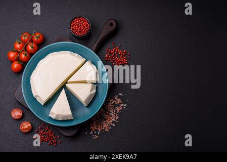 Köstlicher frischer junger Weißkäse aus Kuh- oder Schafmilch auf dunklem Betonhintergrund Stockfoto