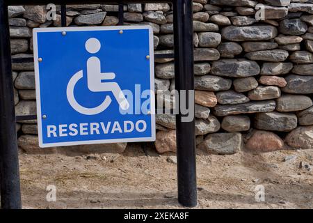 Reserviertes Rollstuhlposter, im Hintergrund eine Kopfsteinmauer an einem Touristenort im Norden Argentiniens. Stockfoto