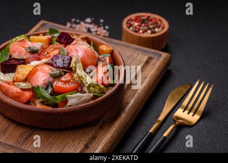 Köstlicher saftiger Salat mit Lachs, Tomaten, Gurke, Kräutern, Kürbiskernen Stockfoto